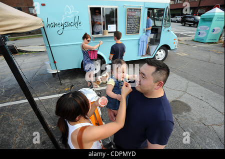 July 13, 2011 - Atlanta, GA, U.S. - ATLANTA, GA - JULY 13: Emery Peng, held by his father Ray, is fed some gelato by his mother Ashley from the Honeysuckle food truck in a parking lot in the Virginia-Highland neighborhood in Atlanta, Georgia on Wednesday, July 13, 2011.  PHOTO CREDIT: ERIK S. LESSER Stock Photo