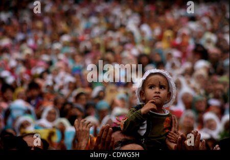 Kashmiri Muslim child looks  as devotees raise their hands for prayers as   head priest displays a relic of Islam's Prophet Mohammed at the Hazratbal shrine following   friday of  Mehraj-u-Alam, believed to mark the ascension of Prophet Mohammed to heaven, in Srinagar, the summercapital of indian ka Stock Photo