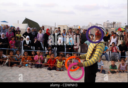 Palestinians watch young clowns as they demonstrate their skills on the beach in Gaza City Friday, July 22, 2011. Photo by Mohammed Asad Stock Photo