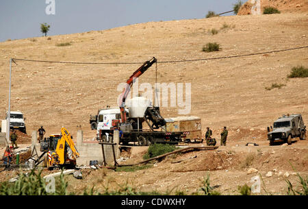 Israeli soldiers surround a bulldozer as it destroys a Palestinian water well in the northern West Bank village of Al-Nassariya, Thursday, Sept. 8, 2011. The Israeli civil administration told Palestinian residents in the village the wells are destroyed for lacking the proper building permits. The mi Stock Photo