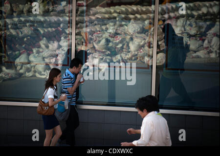 Oct. 31, 2011 - Bangkok, Bangkok, Thailand - Office workers pass by reflection of sandbags placed in front of their office in inner Bangkok. Monday is the first day after Thai prime minister declared long weekend for all workers in anticipation of further inundation of parts of Bangkok. .Thai prime  Stock Photo