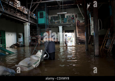 Oct. 31, 2011 - Bangkok, Bangkok, Thailand - Workers move sandbags into the flooded warehouse to prevent further overflow of the floodwaters into residential and business area of Chinatown. Although most of the small businesses are flooded in Chinatown district of Bangkok, shops remain open despite  Stock Photo