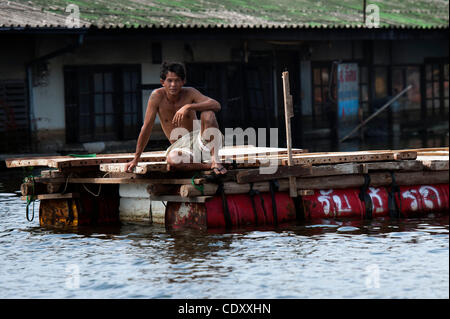 Nov. 10, 2011 - Ayutthaya, Bangkok, Thailand - A man sits on the makeshift raft in one part of town which remain flooded  in Ayutthaya..In may parts of the Ayutthaya town floodwaters have receded, clear up operation started while main tourist attractions remain partially inundated..Floods in Thailan Stock Photo