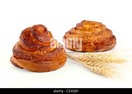 Cinnamon rolls with ear of wheat closeup on a white background Stock Photo