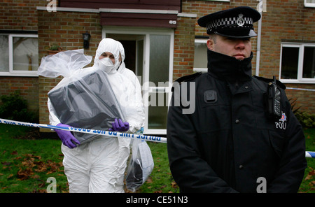 Scene Of Crime Officers remove a computer from a crime scene as a policeman stands guard. Picture by James Boardman. Stock Photo