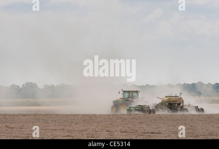Tractor in cloud of dust while performing chemical application on dusty field on farm near Hurlock, Maryland Stock Photo