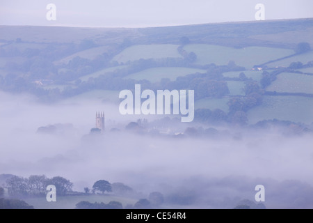 Morning mist swirls around the church tower of Widecombe in the Moor, Dartmoor, Devon, England. Autumn (September) 2011. Stock Photo