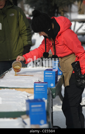 Female pouring maple syrup in snow for a sugar on snow party Stock Photo