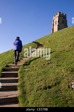 A woman climbs up the steep steps to St Michael's Tower on Glastonbury Tor in Somerset UK Stock Photo