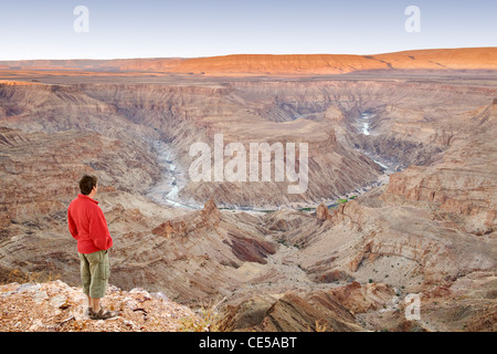 A man stands looking out across the Fish River Canyon in southern Namibia at dawn. Stock Photo