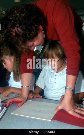 teacher assisting in nursery school class, Highfield Primary School, Hillingdon, Middlesex, UK. Stock Photo