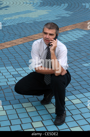 Businessman talking to the phone in paved square. Stock Photo