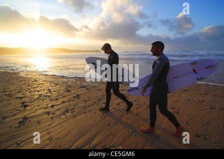 Surfers watch the winter sun go down on Fistral Beach in Newquay, Cornwall, UK. Stock Photo