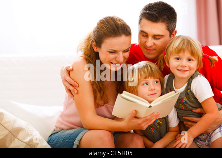 Happy parents reading to twins daughters Stock Photo