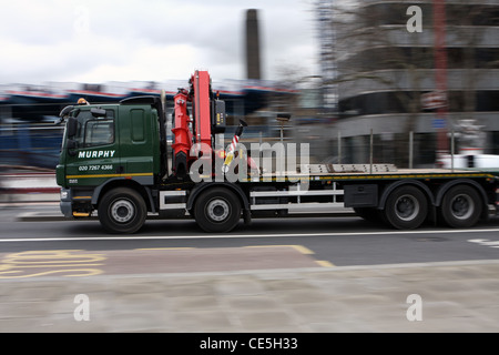 a flatbed articulated truck traveling along a road in London Stock Photo