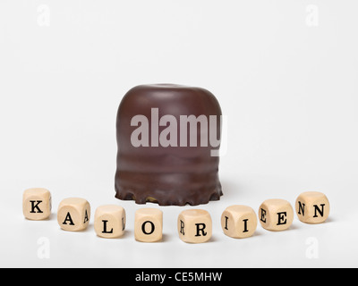Detail photo of a small chocolate-covered cream cake, alongside are cubes which form the word 'calories' in German Stock Photo