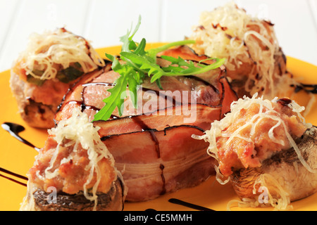 Mushrooms stuffed with ground meat and pork fillet wrapped in bacon Stock Photo