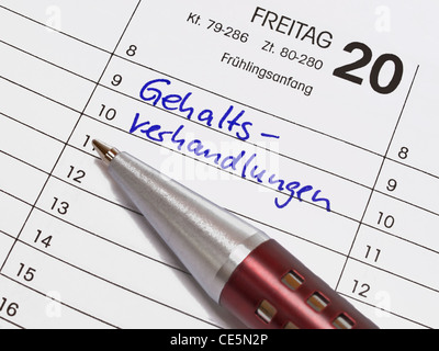 A calendar shows March the 20th, the item salary negotiations is in the calendar written with German words. Beside is a pen. Stock Photo