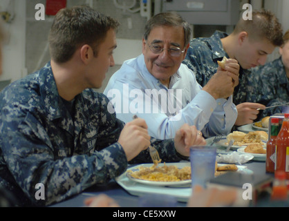 US Secretary of Defense Leon E. Panetta speaks to a sailor during lunch on the mess deck during a visit aboard the aircraft carrier USS Enterprise January 21, 2012 sailing the Atlantic. Stock Photo