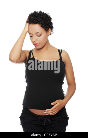 Front view of a pregnant woman holding her hand next to the forehead, having a headache. Isolated on a white background. Stock Photo