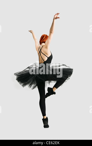 Beautiful ballerina wearing black tutu dancing on gray background Stock Photo