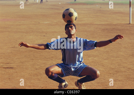 Indian teenager boy balancing football soccer ball on his head ; Shivaji Park ; Bombay ; Mumbai ; Maharashtra ; India ; Asia ; MR#672A Stock Photo