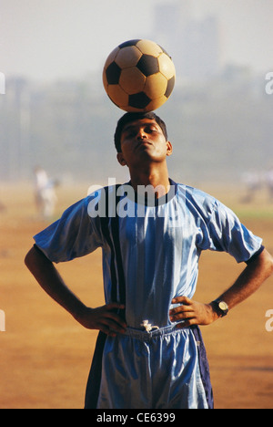 Indian teenager boy balancing football soccer ball on his head ; Shivaji Park ; Bombay ; Mumbai ; Maharashtra ; India ; Asia ; MR#672A Stock Photo