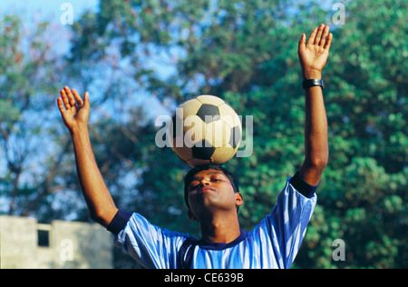 Indian teenager boy balancing football soccer ball on his head ; Shivaji Park ; Bombay ; Mumbai ; Maharashtra ; India ; Asia ; MR#672A Stock Photo