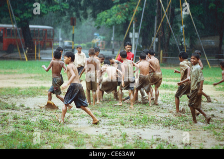 Indian boys playing football in monsoon rain ; Cross Maidan ; Bombay ; Mumbai ; Maharashtra ; India ; Asia Stock Photo