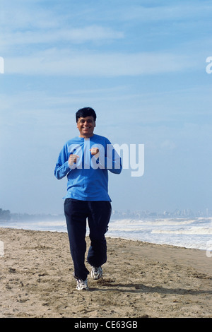Indian senior man jogging on beach ; India ; Asia ; MR#448 Stock Photo
