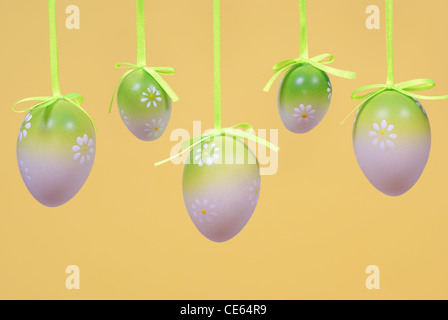 hang eggs on ribbon made on yellow background Stock Photo