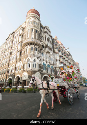 People in a horse drawn carriage on a sightseeing trip around Colaba Mumbai India in front of the Taj Hotel Stock Photo