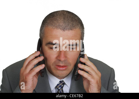 A funny busy businessman using two mobile phones. Stock Photo
