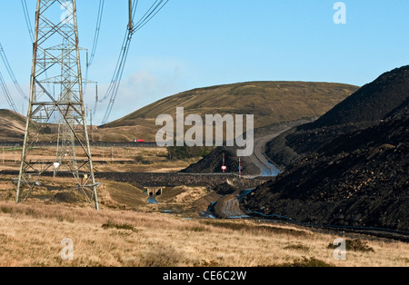 Electricity Power Lines marching across country near Merthyr Tydfil alongside an opencast coal mine Stock Photo