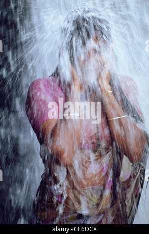 Indian woman bathing under waterfall ; mundan thurai ; india Stock Photo