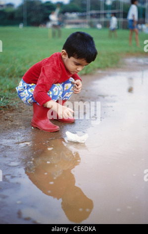 Paper boat in puddle outdoor in rainy weather Stock Photo - Alamy