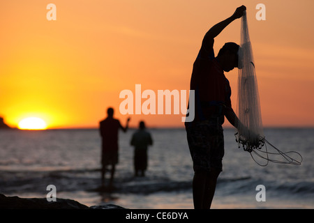 Costa Rican men fish with nets from the rocks on the Beach at Playa ...