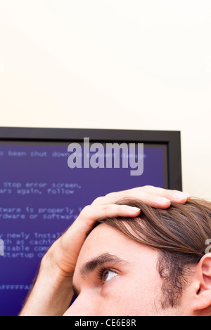 Unhappy man looking at computer error message. Blue Screen of Death. Stock Photo