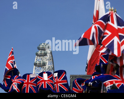 An in focus London Eye towers above a souvenirs stall with union jack flags and hats. Stock Photo