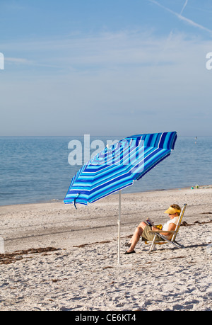 Older Woman Reading under Beach Umbrella - Florida Stock Photo