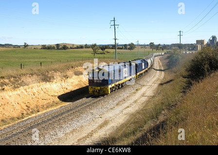 A train travelling on a single line between an industrial complex and the main line Stock Photo