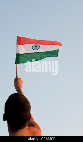 Indian man holding an Indian flag against a blue sky. India Stock Photo