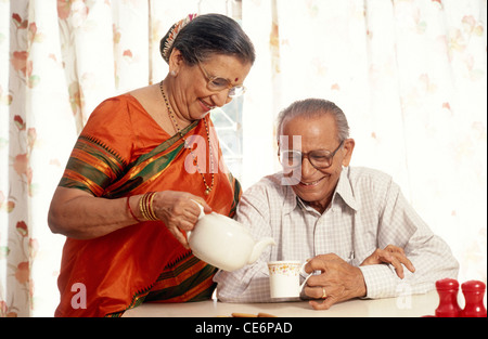 Old woman pouring tea in cup of old man MR#318&319 Stock Photo