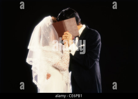 Christen bride and bridegroom kissing hiding face in marriage ceremony Stock Photo