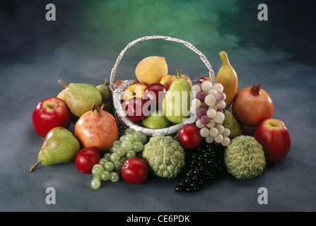 Mix fruits in basket apples pears green grapes red grapes peach plums custard apple pomegranate banana on grey background Stock Photo
