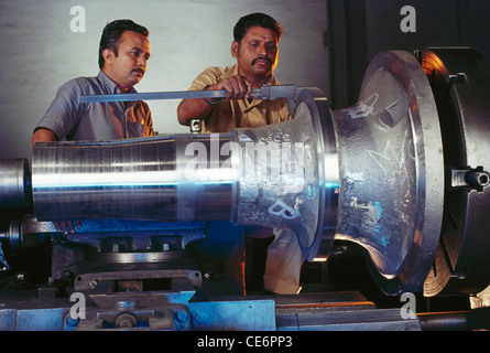 Indian workers working on lathe machine in engineering factory ; india ; asia Stock Photo
