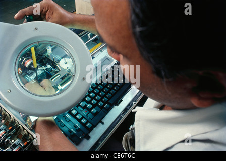 typewriter manufacture tightening screw looking through magnifying glass in factory ; india ; asia Stock Photo