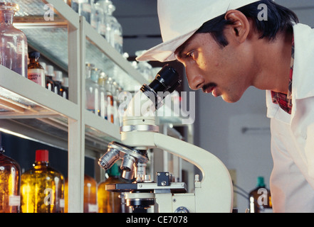 Man looking through microscope in lab Stock Photo