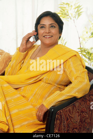 senior woman sitting in her house on a sofa talking on mobile phone MR#449 Stock Photo