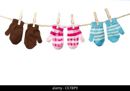 Three pairs of mittens hanging on a clothes line isolated on a white background Stock Photo